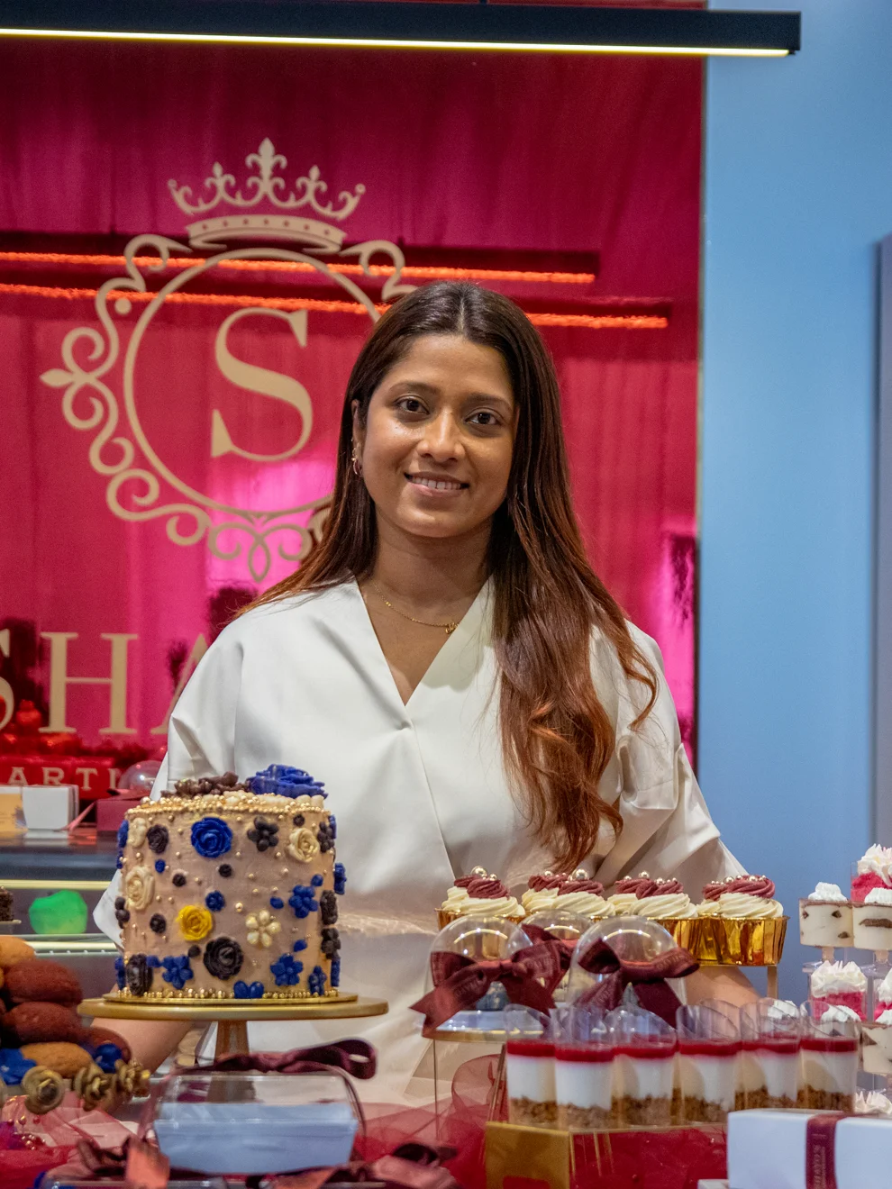 Shayo at the dessert counter, surrounded by her handcrafted cakes and dessert cups